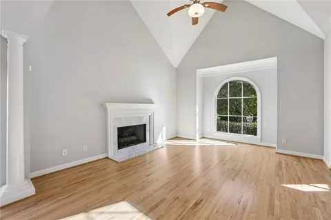 an empty room with wooden floor fireplace and windows