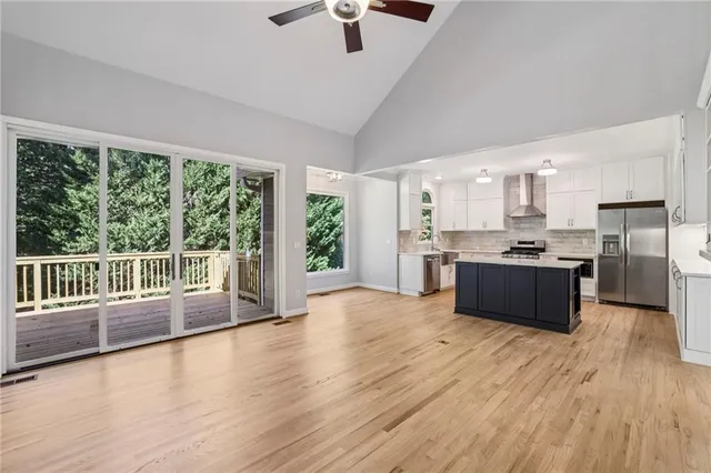 a large kitchen with stainless steel appliances granite countertop a stove a sink dishwasher a refrigerator and a dining table with wooden floor