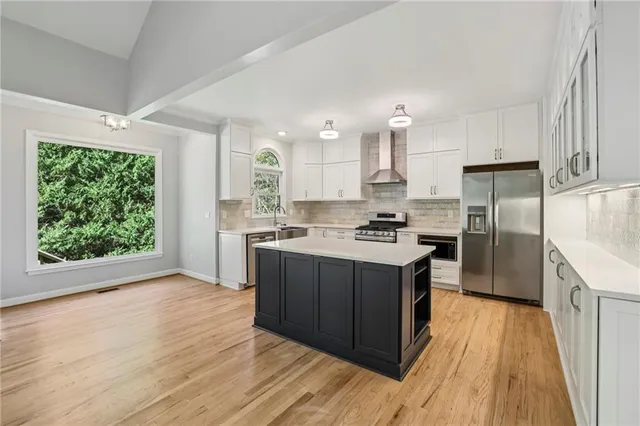 a kitchen with stainless steel appliances granite countertop a stove a sink dishwasher a refrigerator and a oven with wooden floor