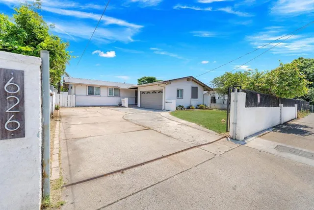 a view of a house with a yard and potted plants