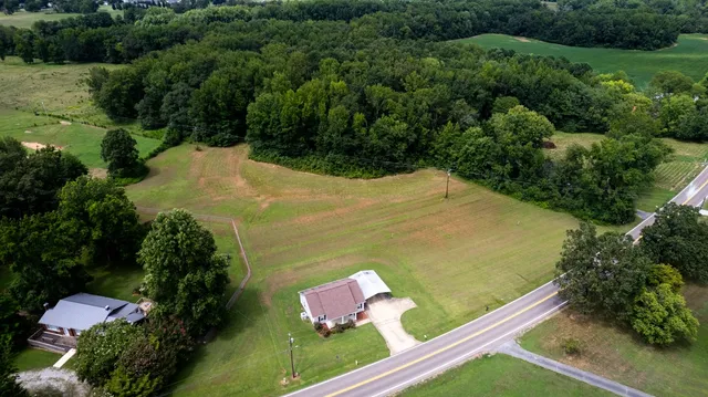an aerial view of a residential houses with outdoor space and trees