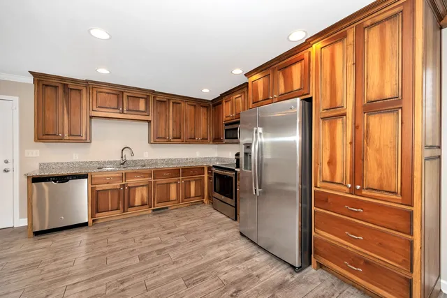 a kitchen with stainless steel appliances granite countertop a refrigerator and a stove top oven
