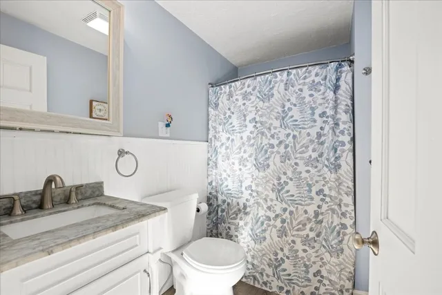 a bathroom with a granite countertop sink toilet and a mirror
