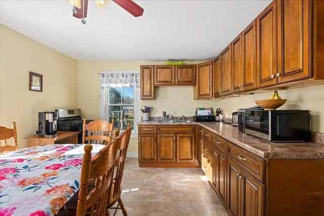 a kitchen with stainless steel appliances granite countertop a sink a stove a refrigerator with a dining table and chairs