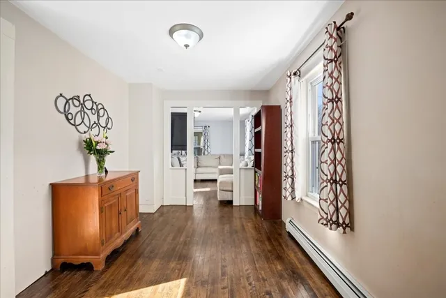 a view of a hallway to a livingroom with wooden floor and furniture