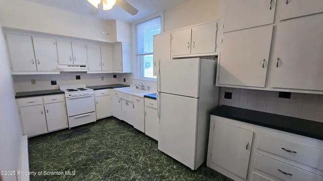 a kitchen with white cabinets and white appliances
