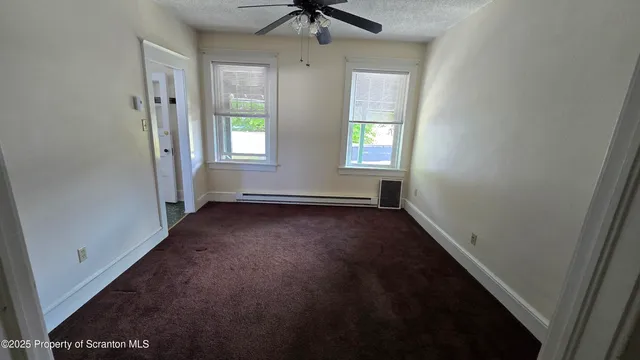 an empty room with windows and fan