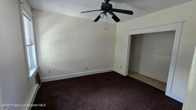an empty room with a window and a fan