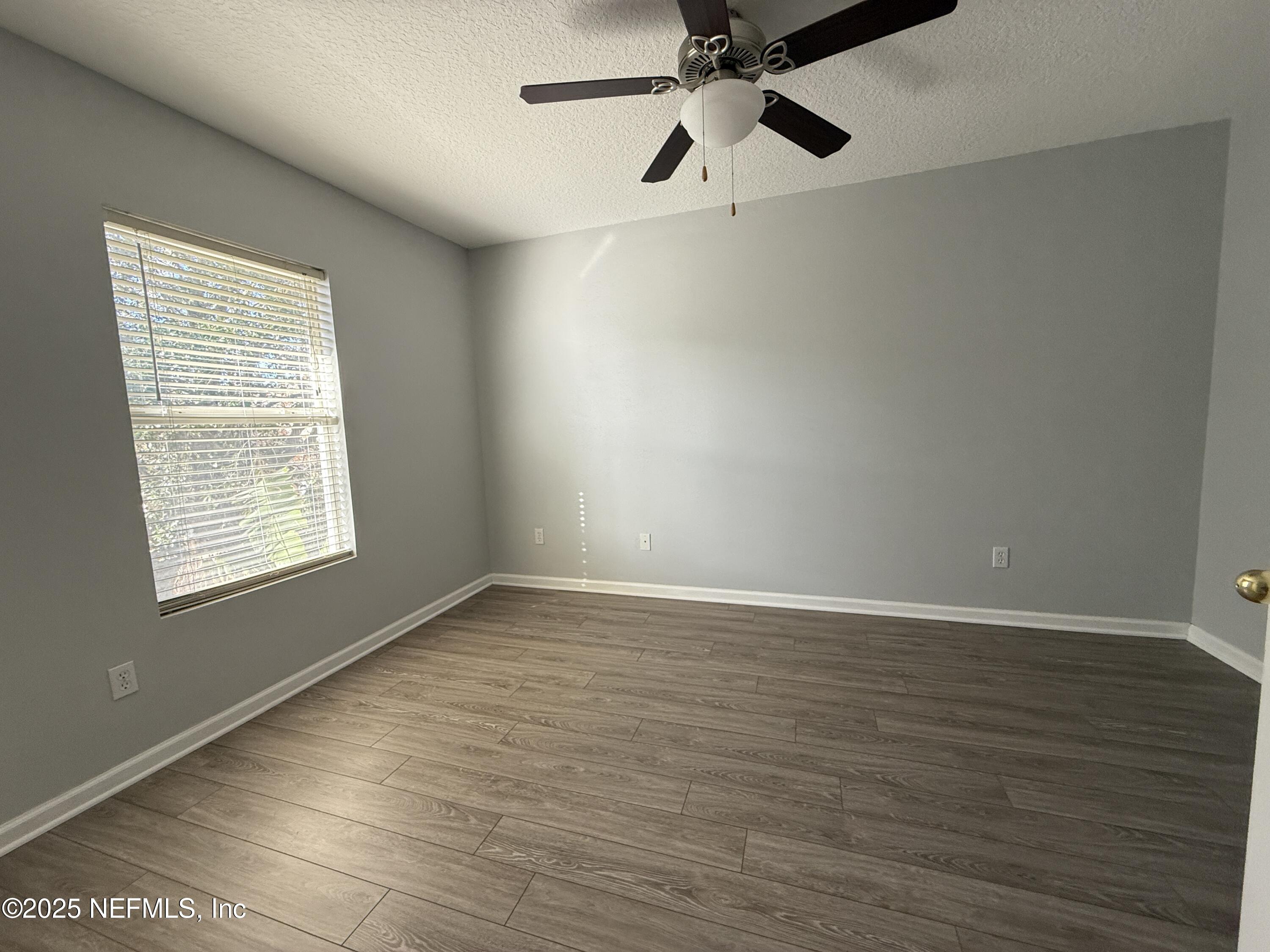 1865 Green Springs Circle, Unit C Fleming Island, FL 32003 - Photo 19 of 29 an empty room with wooden floor fan and windows