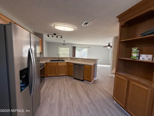 a view of a big room with wooden floor and a kitchen