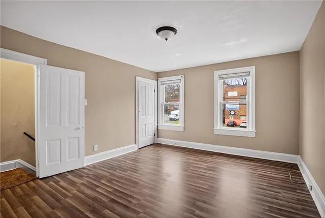 a view of empty room with wooden floor and fireplace