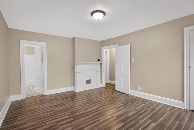 a view of an empty room with window and wooden floor