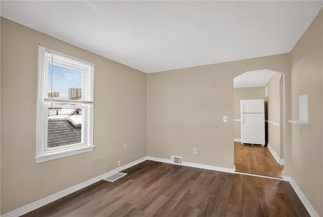 a view of an empty room with wooden floor and closet