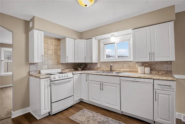 a kitchen with a sink a stove cabinets and wooden floor