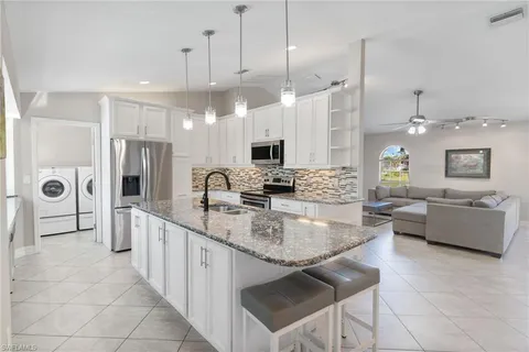 a large kitchen with kitchen island a large counter top space a sink stainless steel appliances and cabinets