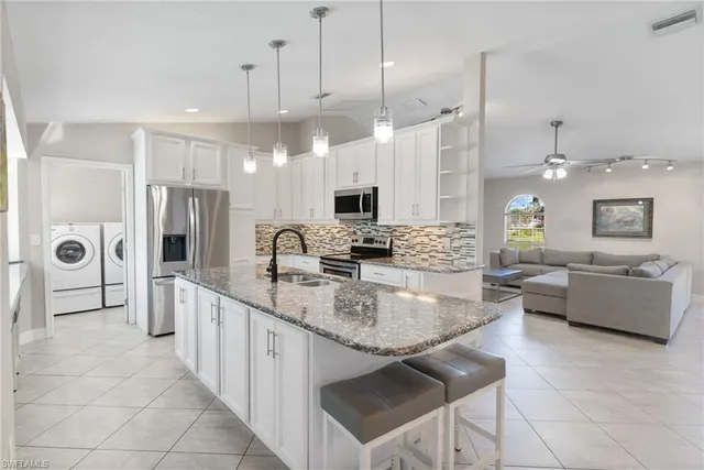 a large kitchen with kitchen island a large counter top space a sink stainless steel appliances and cabinets