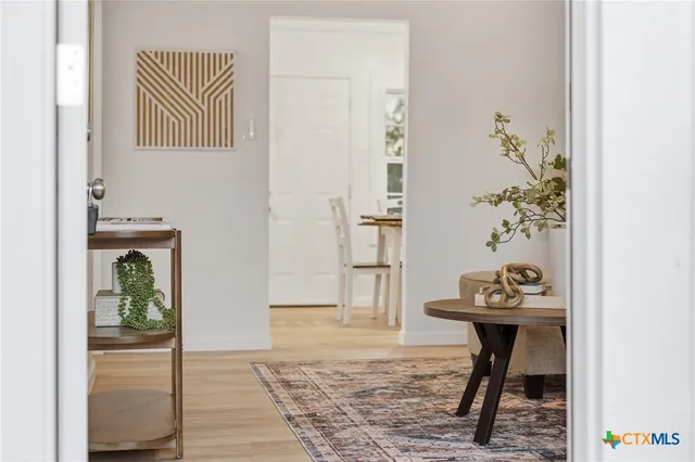 a view of a hallway with wooden floor and a dining table