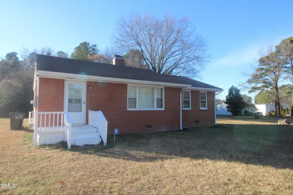 a view of a house with a yard and large tree
