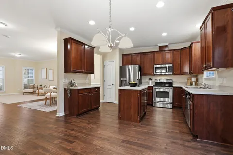 a kitchen with kitchen island granite countertop wooden floors stainless steel appliances a sink and a window