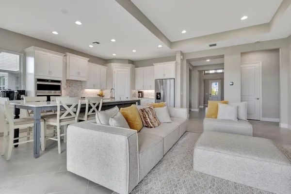 a living room with stainless steel appliances furniture white walls and kitchen view