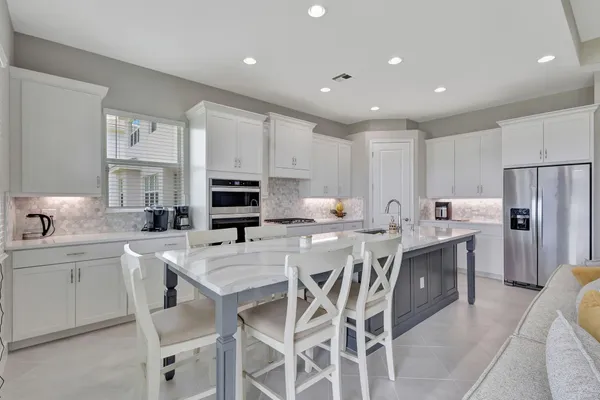 a kitchen with stainless steel appliances granite countertop a table chairs sink refrigerator and microwave