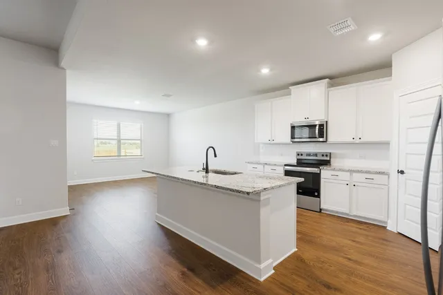 an empty room with wooden floor ceiling fan and windows