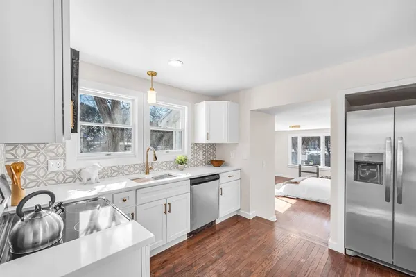 a kitchen with a sink cabinets stainless steel appliances and windows