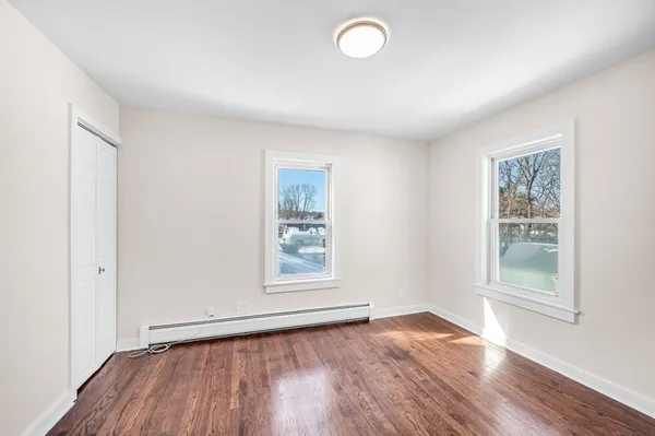 an empty room with wooden floor and windows