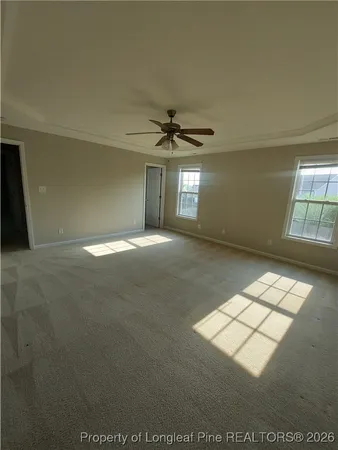 an empty room with windows and ceiling fan