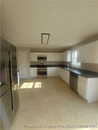 a kitchen with stainless steel appliances granite countertop a refrigerator a stove and a sink