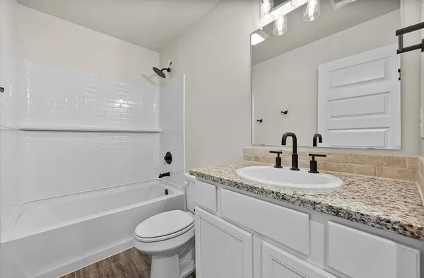 a bathroom with a granite countertop toilet sink and mirror