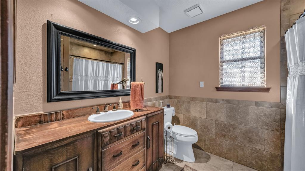 351 Don Propp Road Azle, TX 76020 - Photo 23 of 36 a bathroom with a granite countertop toilet a sink a mirror and a window