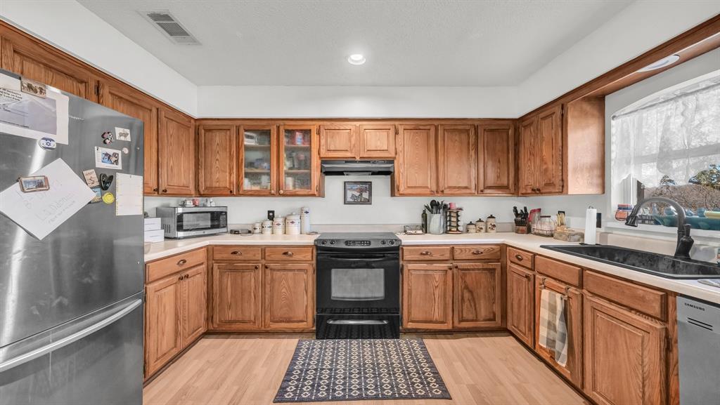 351 Don Propp Road Azle, TX 76020 - Photo 10 of 36 a kitchen with stainless steel appliances granite countertop a stove top oven a sink dishwasher and a refrigerator with wooden cabinets