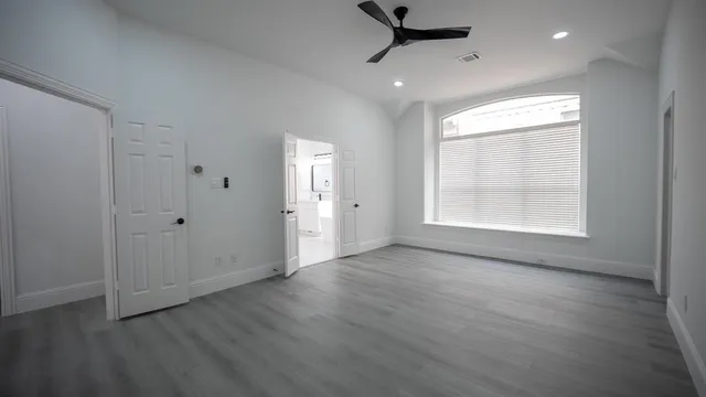 a view of an empty room with a window and wooden floor