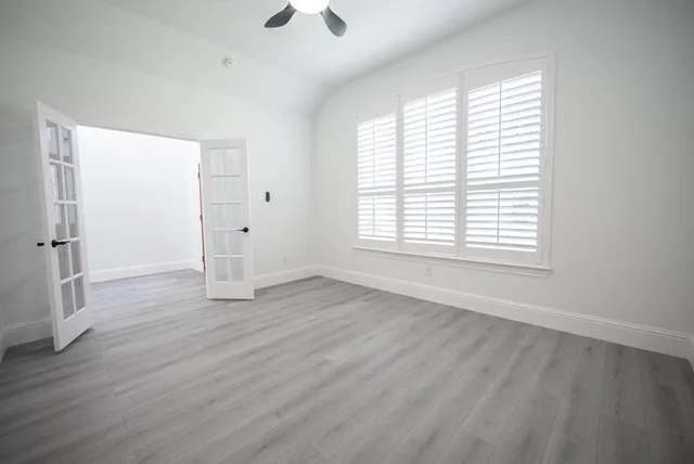 an empty room with wooden floor and windows