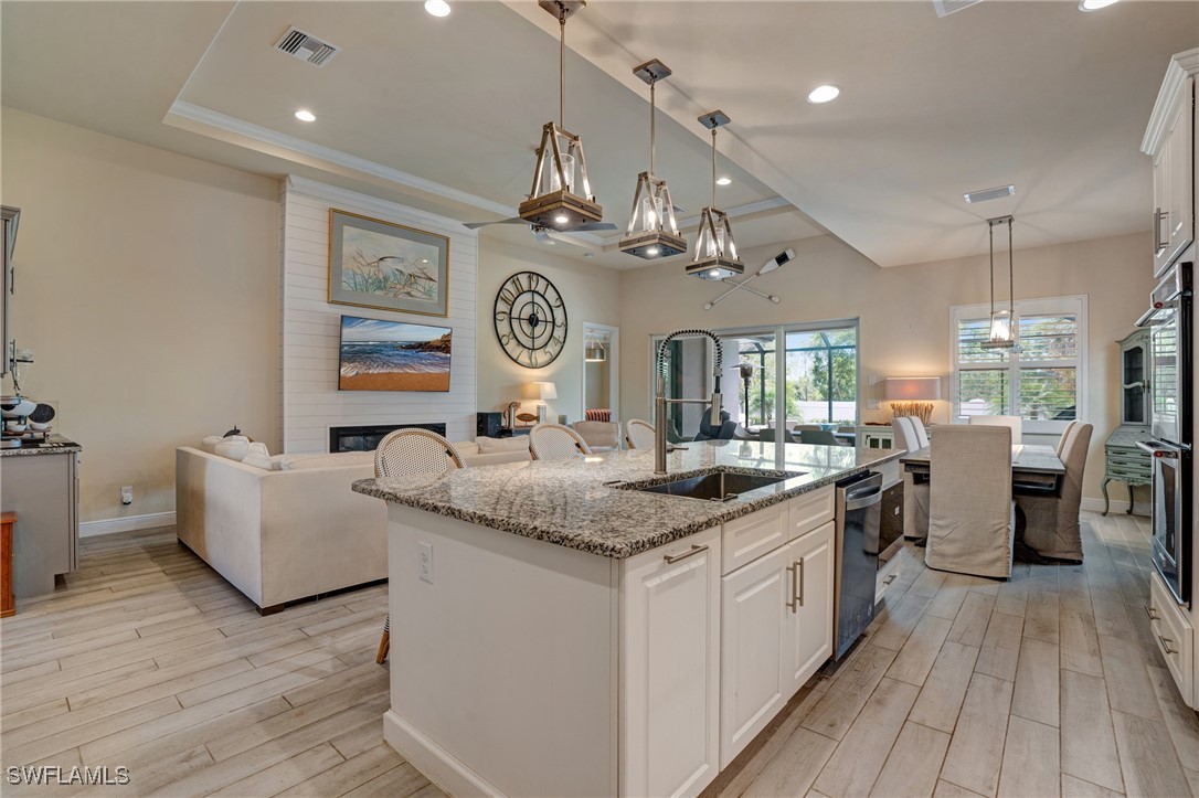 9292 Cayman Drive Naples, FL 34114 - Photo 5 of 50 a kitchen with granite countertop a sink dishwasher a stove and white cabinets with wooden floor
