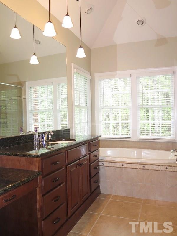 809 Nolstead Court Raleigh, NC 27614 - Photo 12 of 23 a bathroom with a granite countertop sink a large mirror and a bathtub next to a window
