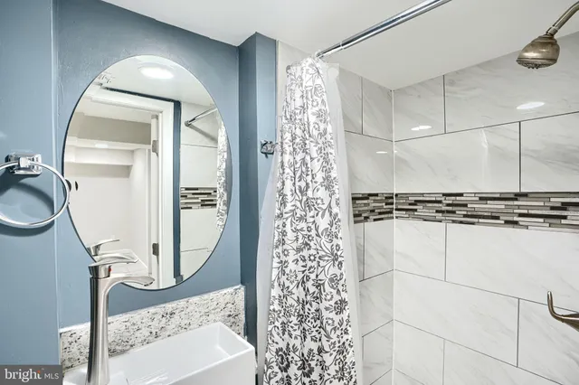a bathroom with a granite countertop shower a mirror and a sink