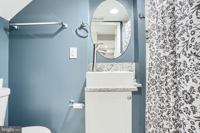 a bathroom with a granite countertop sink mirror vanity and toilet