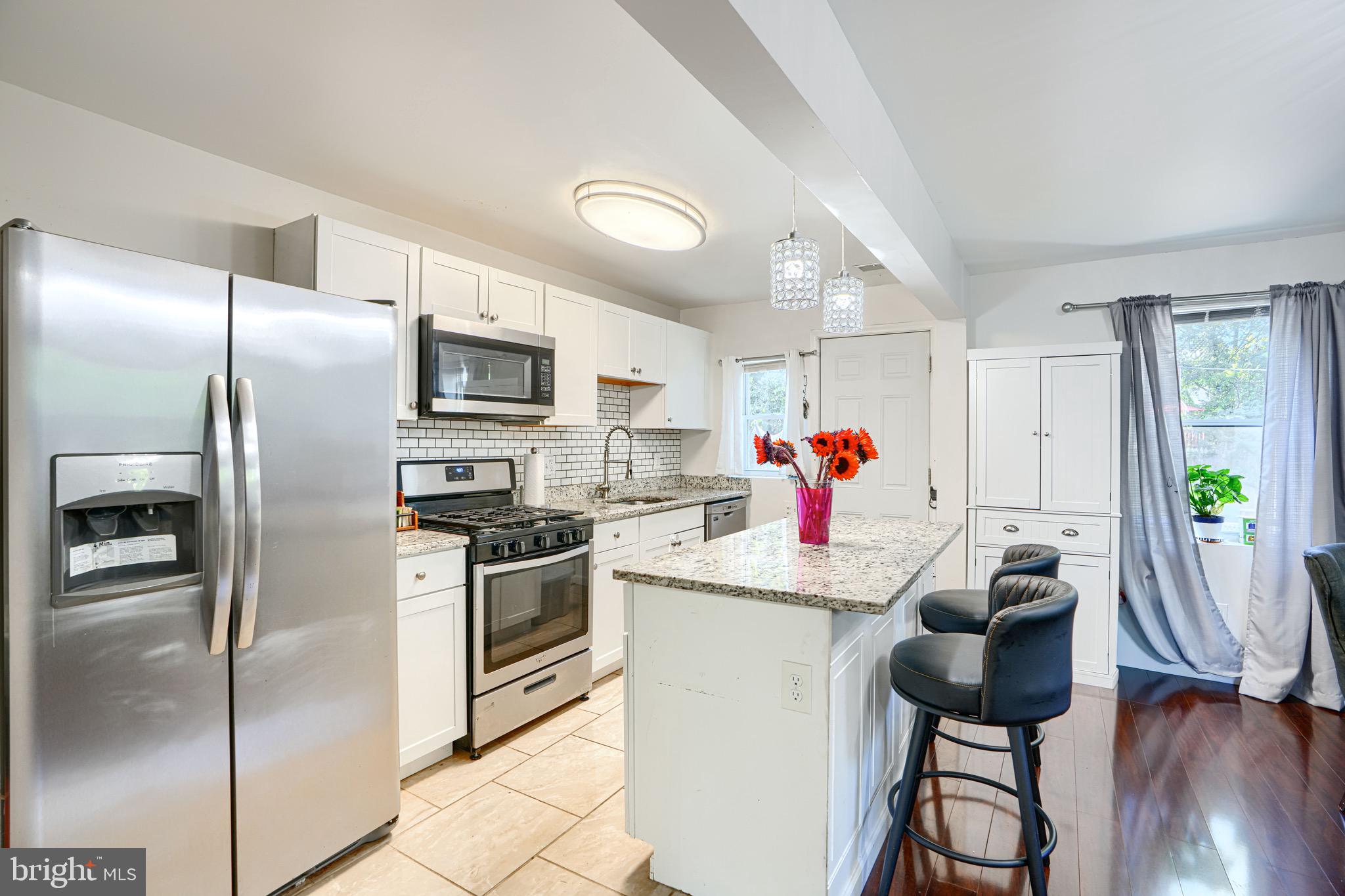 4054 Hilton Road Baltimore, MD 21215 - Photo 6 of 26 a kitchen with stainless steel appliances granite countertop a refrigerator oven a sink dishwasher and white cabinets next to a window
