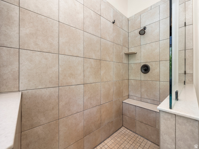 255 East 1200 North Mapleton, UT 84664 - Photo 16 of 37 Walk-in shower with full-height tile surround, integrated bench seating, built-in shelving, dark bronze fixtures, and a glass partition