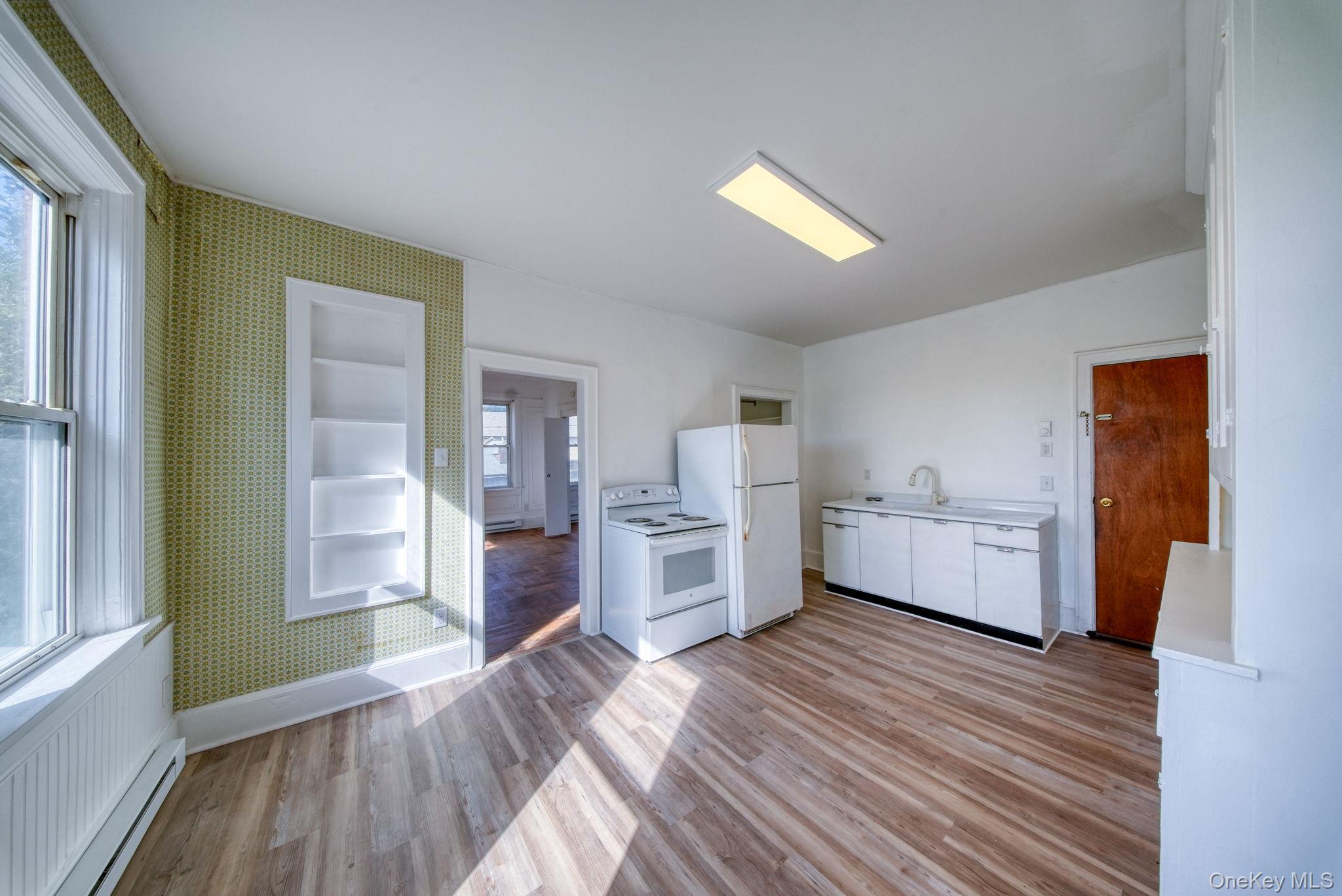 9 Mongaup Road Hurleyville, NY 12747 - Photo 12 of 35 Kitchen featuring white cabinetry, wallpapered walls, light countertops, light wood-type flooring, and a baseboard radiator