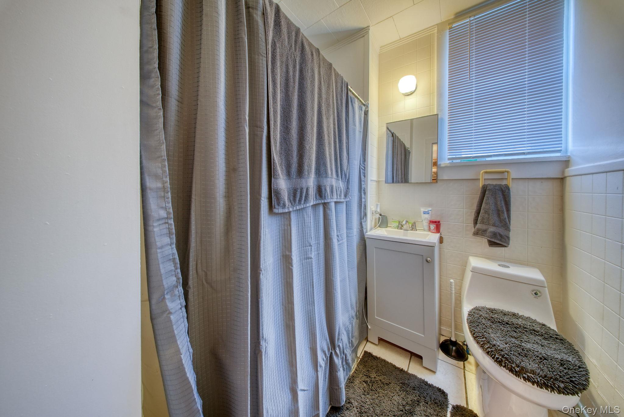 9 Mongaup Road Hurleyville, NY 12747 - Photo 34 of 35 Bathroom with tile walls, vanity, light tile patterned floors, and a shower with curtain