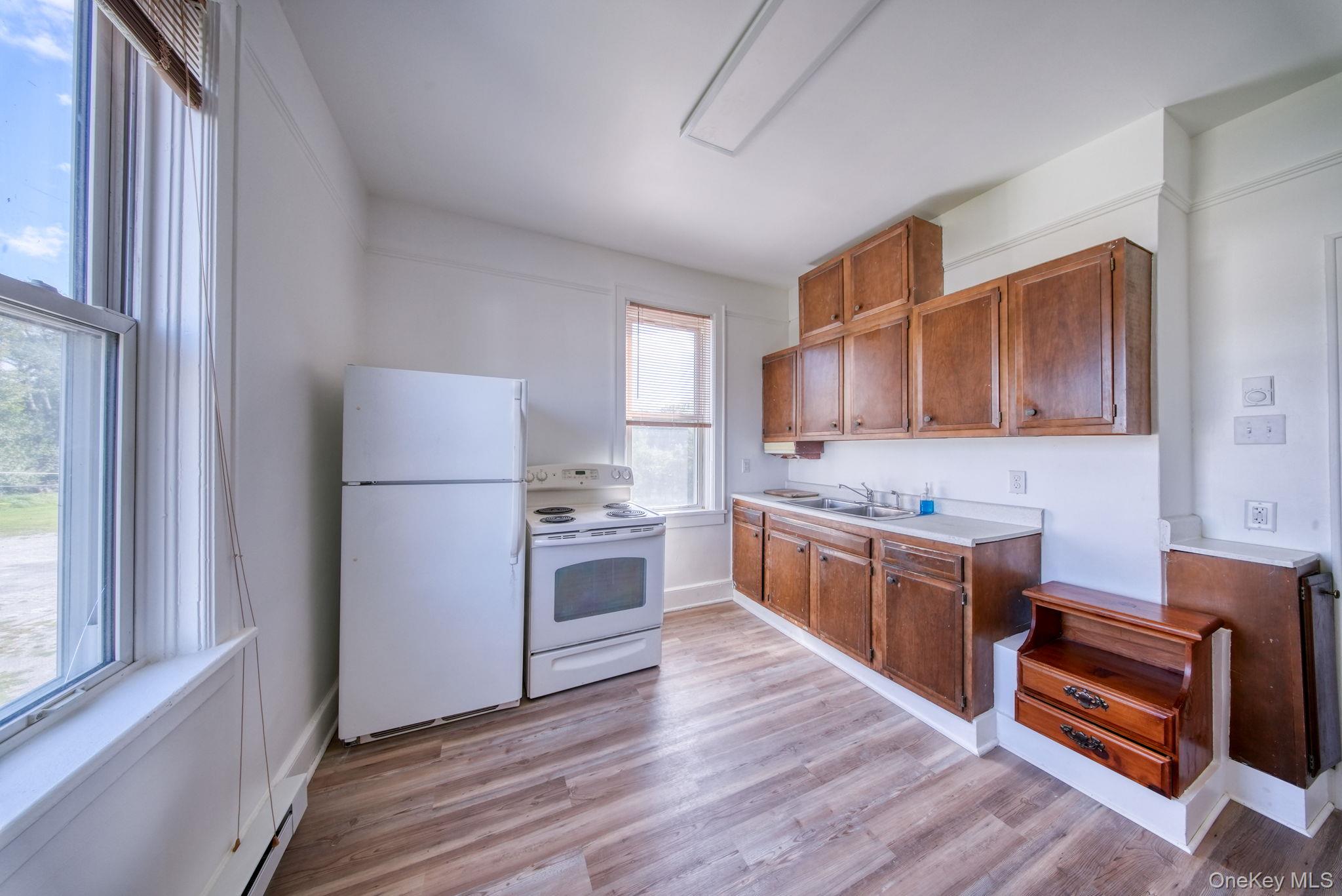 9 Mongaup Road Hurleyville, NY 12747 - Photo 10 of 35 Kitchen with brown cabinets, white appliances, light countertops, a baseboard radiator, and light wood-style flooring