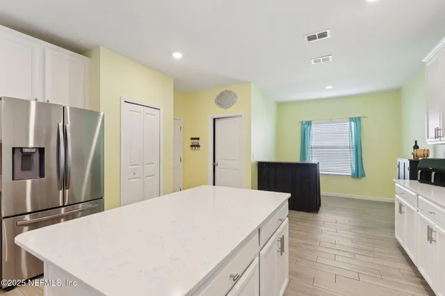 a kitchen with stainless steel appliances kitchen island granite countertop a refrigerator a stove and a sink with wooden floor