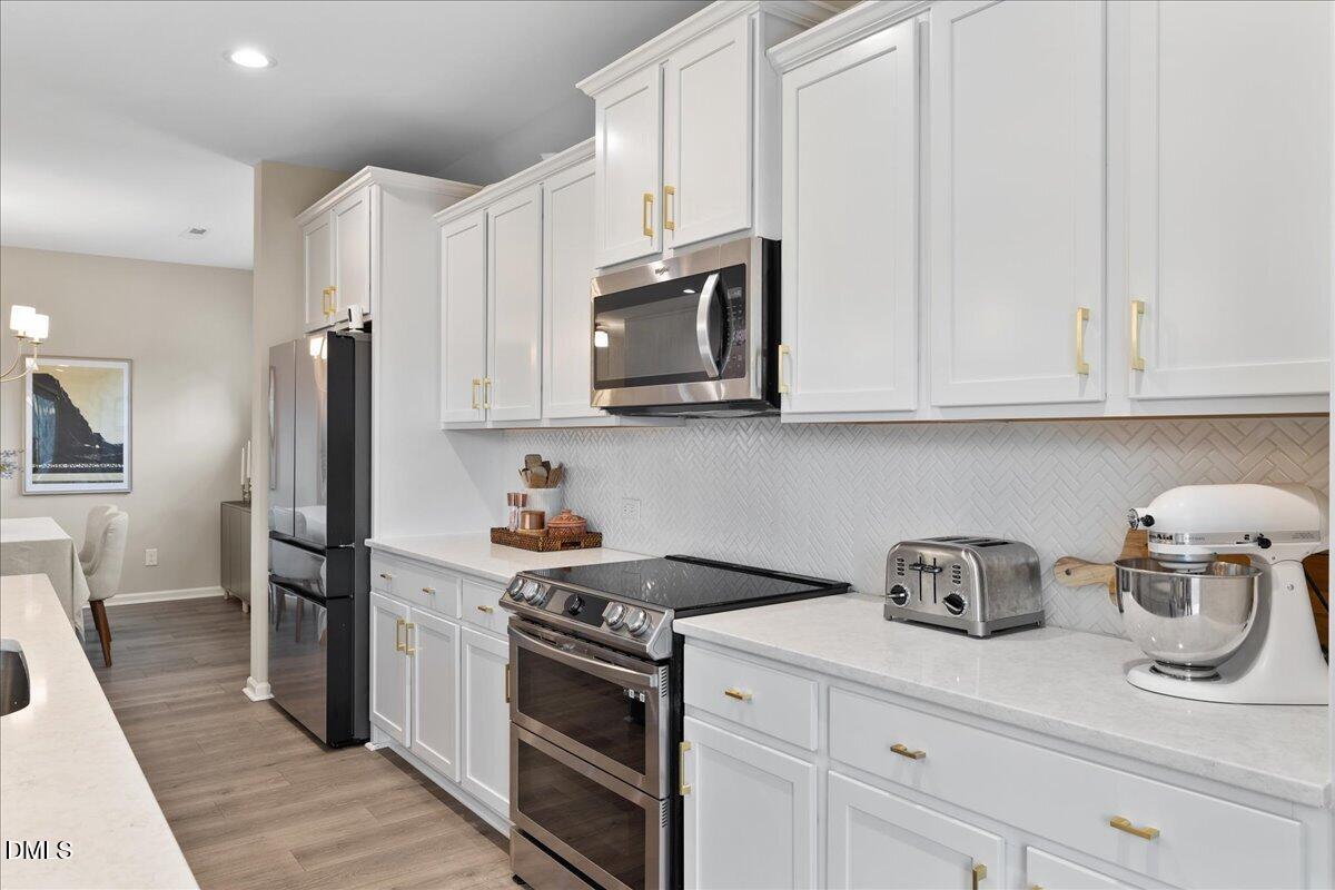 1237 Huffington Oak Drive Willow Spring, NC 27592 - Photo 11 of 34 a kitchen with stainless steel appliances granite countertop a refrigerator stove and white cabinets