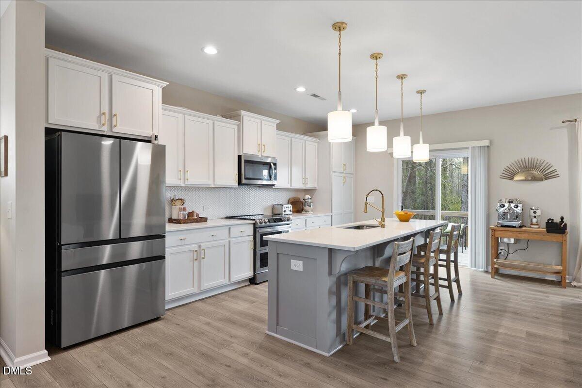 1237 Huffington Oak Drive Willow Spring, NC 27592 - Photo 9 of 34 a kitchen with kitchen island granite countertop a sink a center island and stainless steel appliances