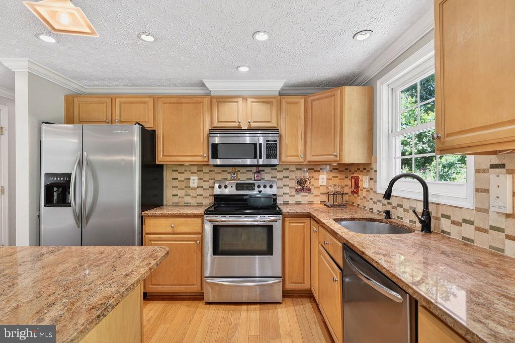 8471 Great Lake Lane Springfield, VA 22153 - Photo 10 of 65 a kitchen with stainless steel appliances granite countertop a sink a stove a refrigerator with a sink