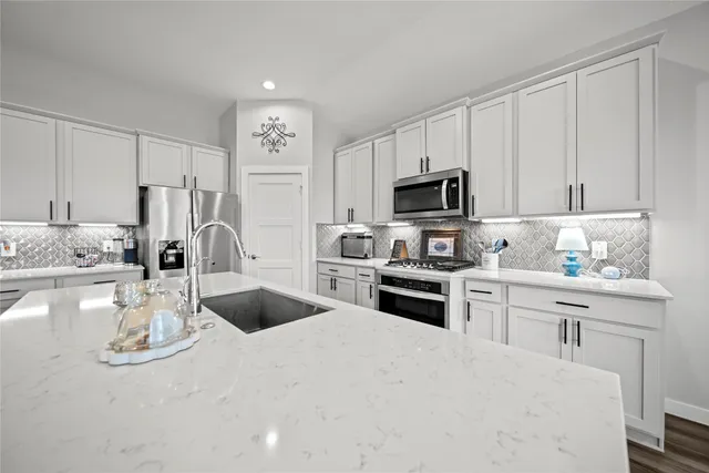 a kitchen with granite countertop a sink stove and refrigerator