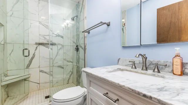 a bathroom with a granite countertop sink toilet and shower